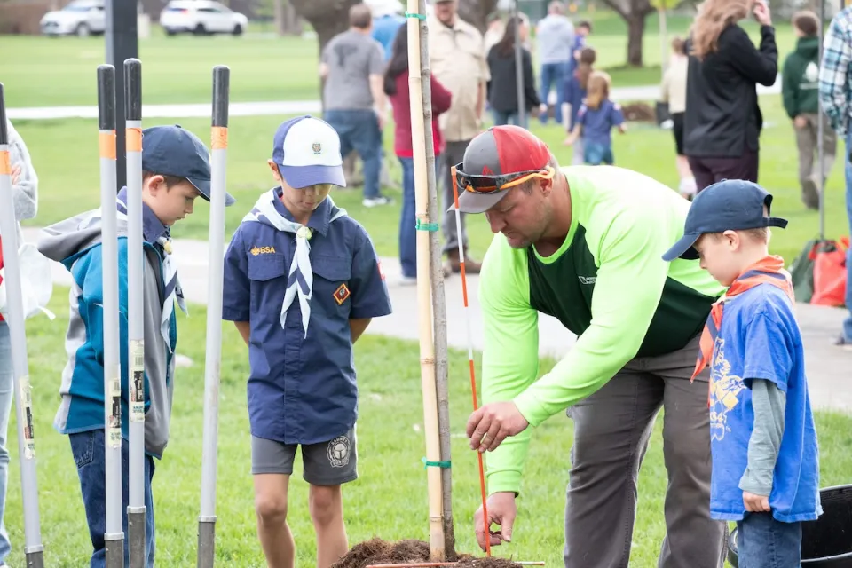 Adults and children planting trees during Arbor Day event in Lakewood, Colorado.